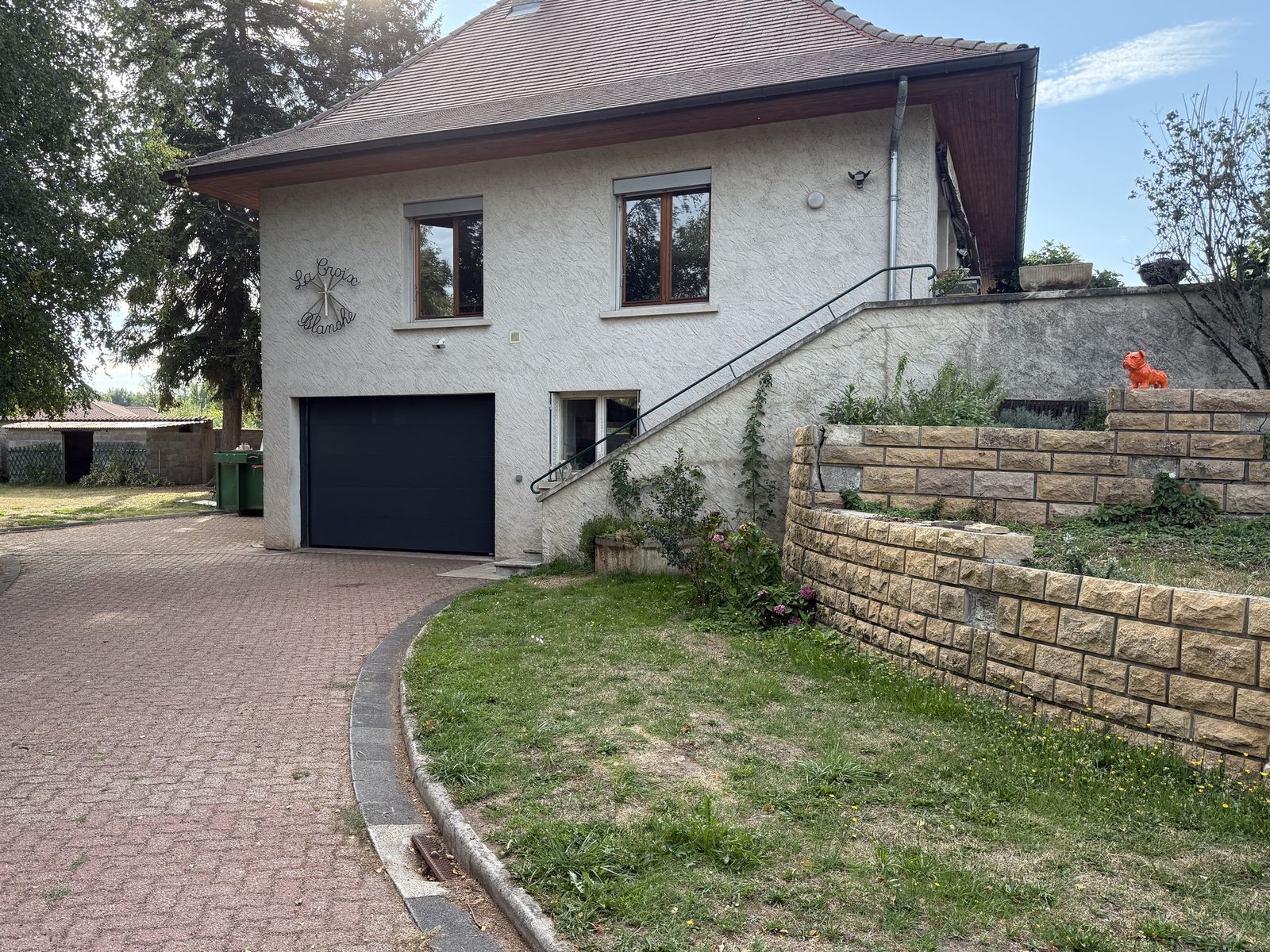 Maison côté entrée, garage et mur en pierre